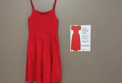 photo of a red dress and a poster hanging on a wall