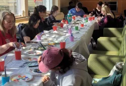 Participants in the Scatter Stones event paint rocks with messages of respect, consent, compassion, and care.