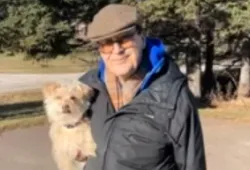Photo of man standing outside holding a small dog
