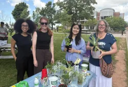 Photo of four people gathered around a table holding plant trimmings and cuttings.