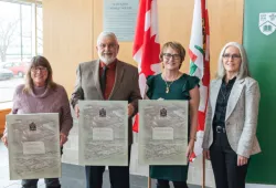 Photo of four people standing in a group, three of them holding canvas recognition frames