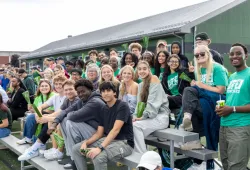 photo of smiling students sitting on bleachers