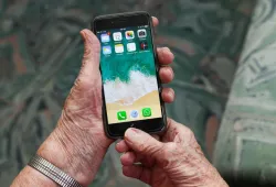 Senior holding phone showing apps