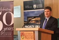 photo of man speaking at a podium flanked by pull up banners