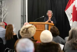 Woman standing at podium with hands clasped