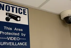 photo of a security camera alongside a sign with a notice