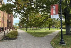 Photo of welcome banner on lampstand in campus quadrangle along a brick walkway