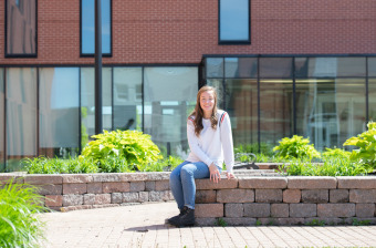 upei nursing graduate shayna conway sitting outside in maclauchlan plaza on upei campus