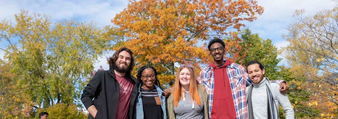 five students posing by a large maple tree