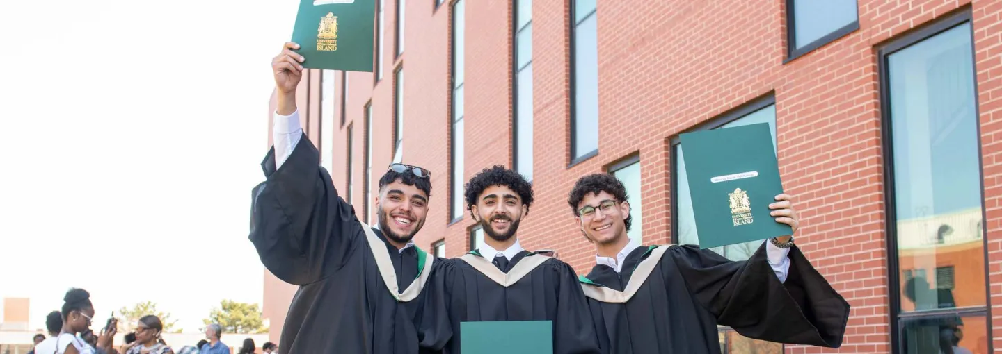three smiling UPEI graduates holding degrees