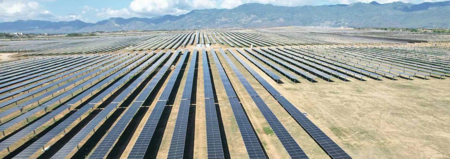 a valley field of solar arrays with mountains in the background