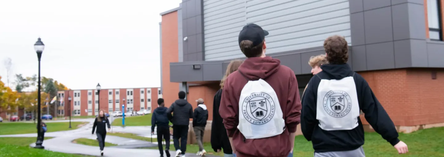 students wearing white UPEI bags walking on campus
