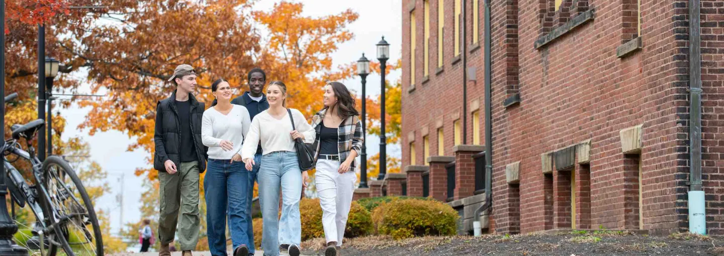 five students in fall walking in front of SDU Main Building