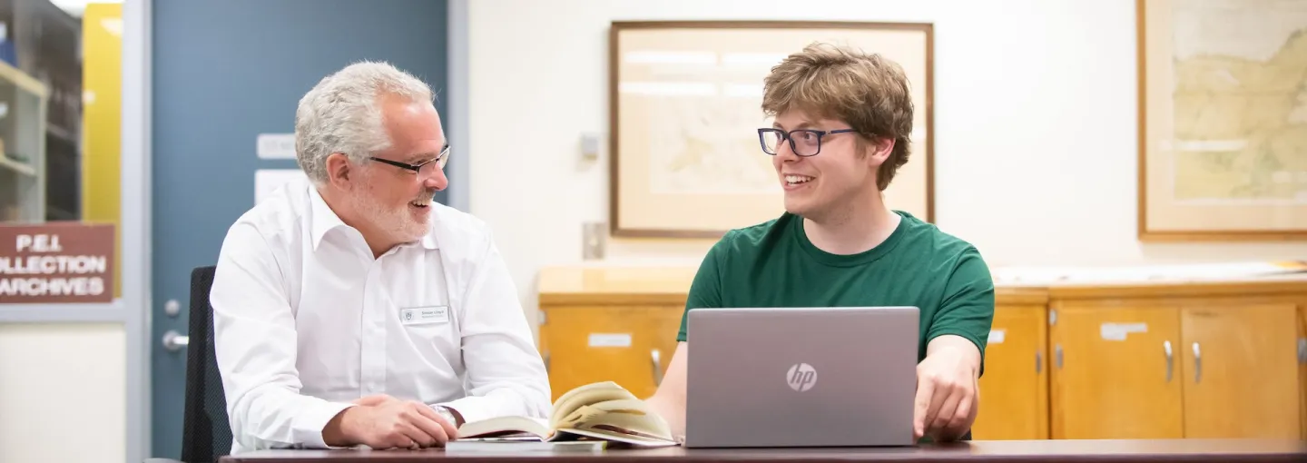 two people talking in front of a laptop computer