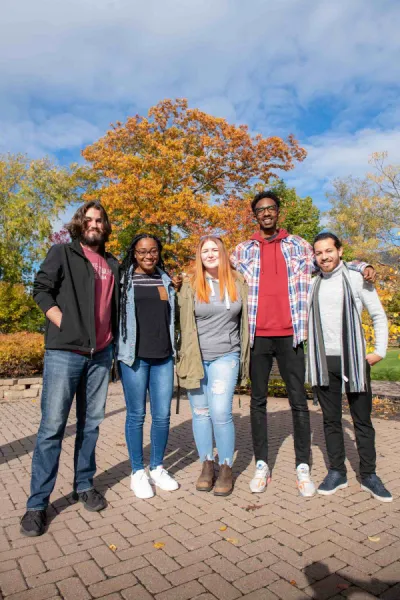 five students posing by a large maple tree