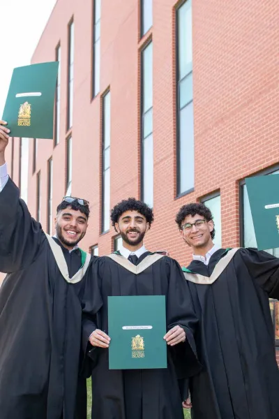 three smiling UPEI graduates holding degrees