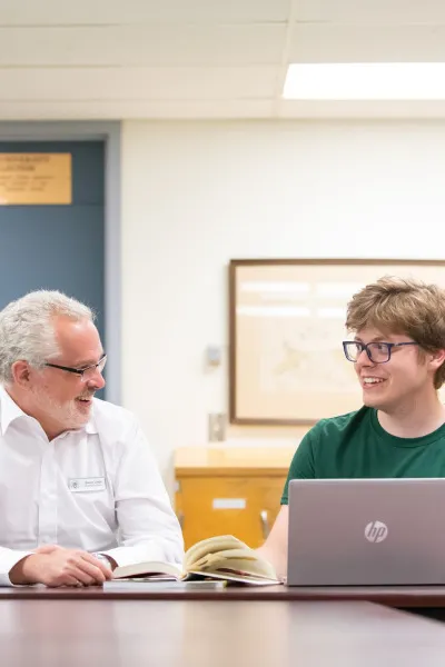 two people talking in front of a laptop computer