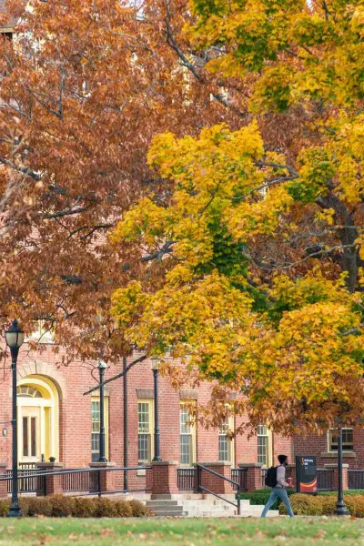 a student walking past SDU Main Building in fall