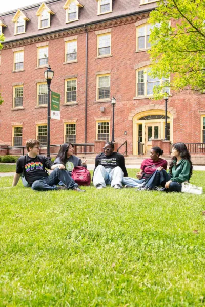five students sitting in front of a large brick building