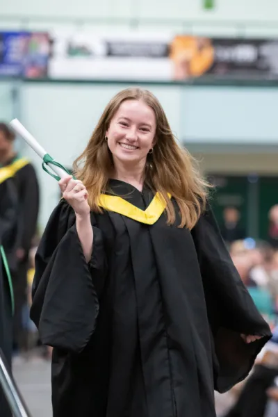 a happy student with gold hood at Convocation
