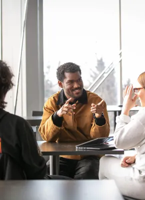 three students talking at a small table