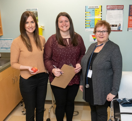 three health professionals standing in an examination room
