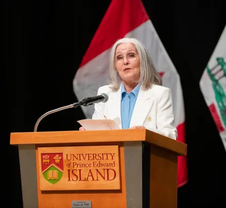 Dr. Wendy Rogers at a podium with flags in the background