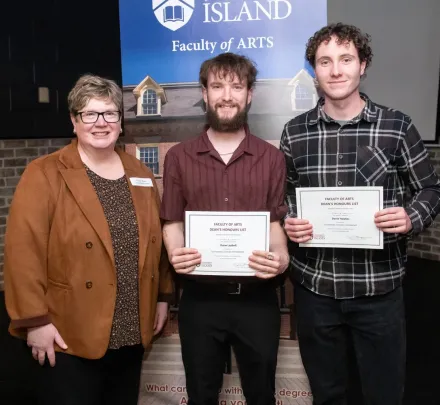 a faculty member presenting awards to two students