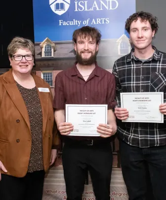 a faculty member presenting awards to two students