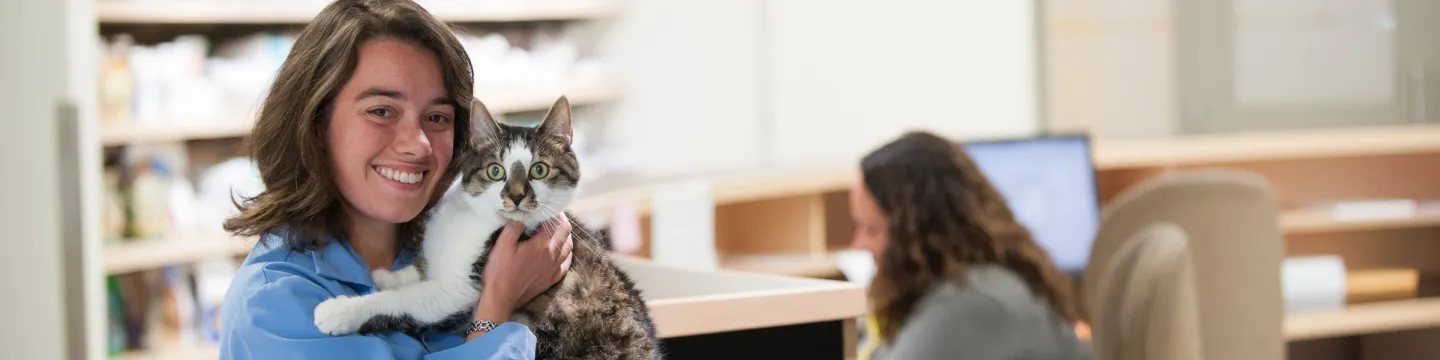 A student poses with a cat in the Veterinary Teaching Hospital