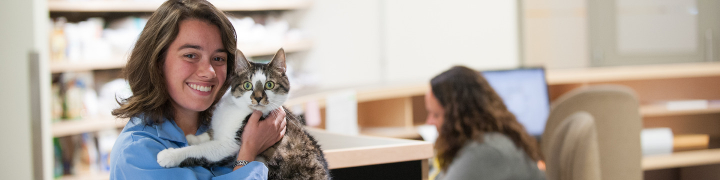 A student poses with a cat in the Veterinary Teaching Hospital