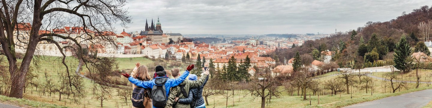 four students standing with their backs to the camera, looking at a european cityscape