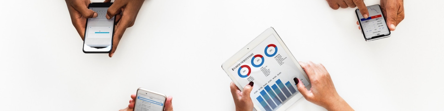 four business professionals' hands with mobile devices