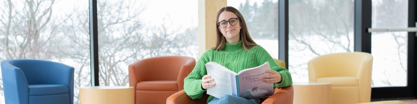 upei climate change student zoe furlotte reading a textbook with bright windows in the background
