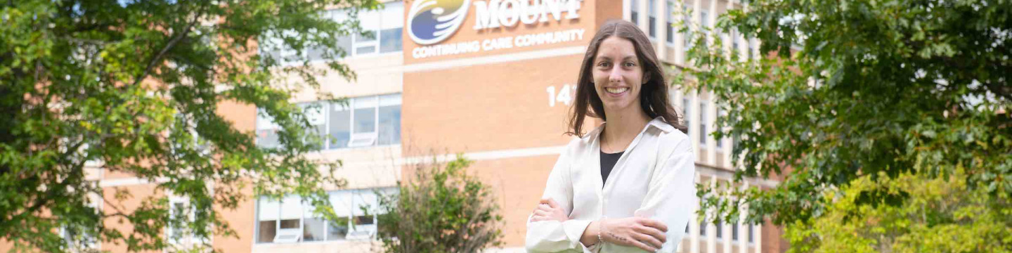 Nutrition Services Manager and Dietitian Katie Nordby standing by the Mount Continuing Care Community building