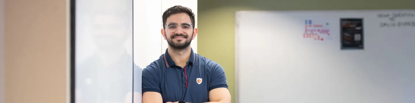 UPEI mathematics and economics student Samuel leaning up to a classroom whiteboard