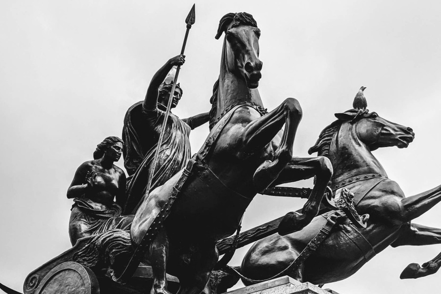 statue of man riding a chariot with two horses