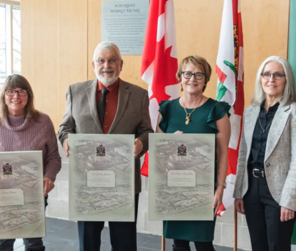 Photo of four people standing in a group, three of them holding canvas recognition frames