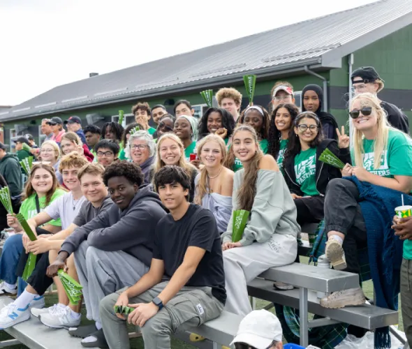 photo of smiling students sitting on bleachers