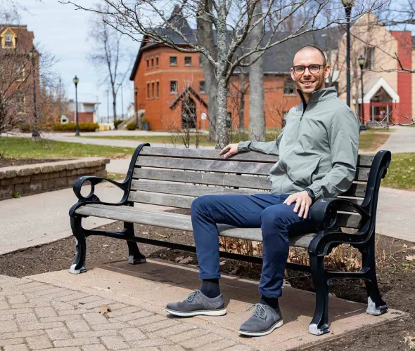 Peter Blanchard sitting on a bench in UPEI's quad