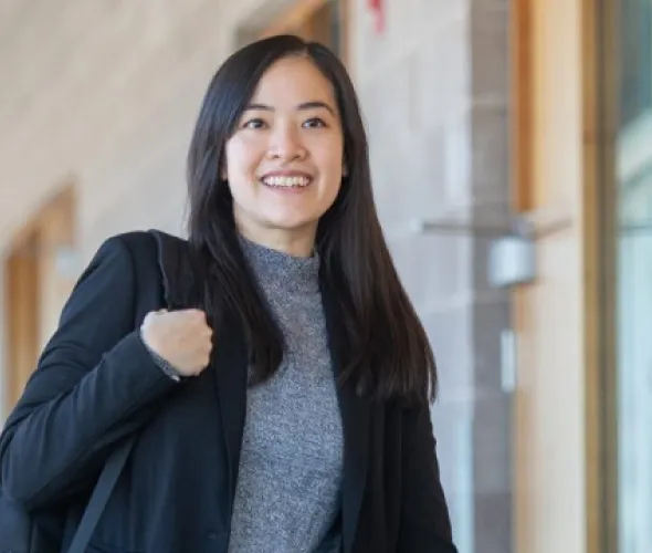 a smiling student walking in a hall